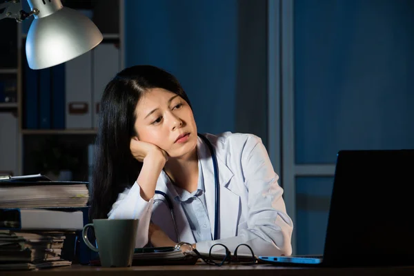 Перегруженная работой женщина-врач сидит за столом — стоковое фото