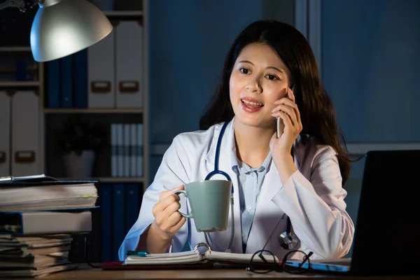 Medico donna bere caffè e fare chiamata — Foto Stock