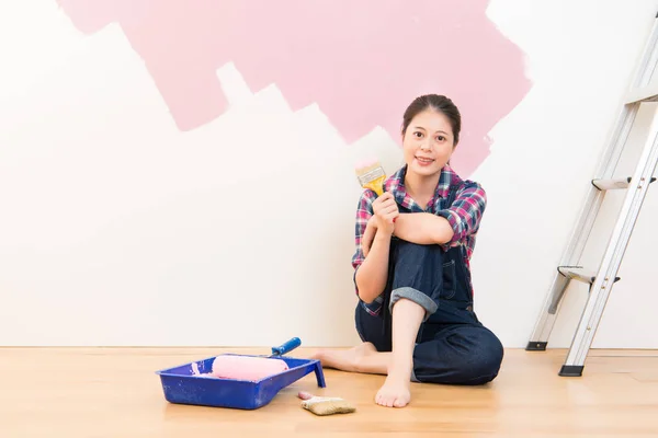 Donna pittrice seduta al piano vicino al muro — Foto Stock