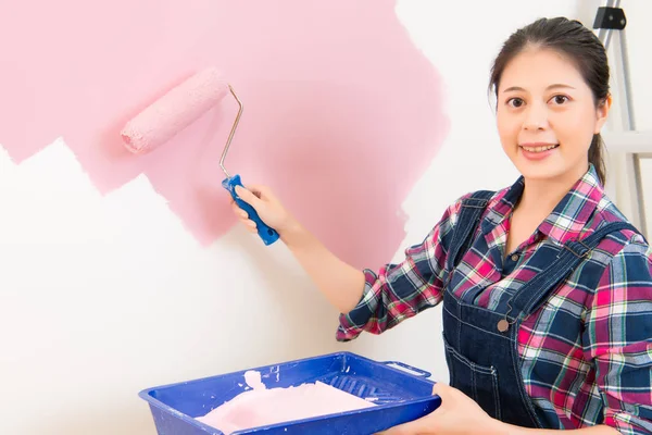 Donna sorridente pittura muro a casa — Foto Stock