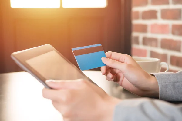 Молодая женщина использует кредитную карту для оплаты на планшете — стоковое фото