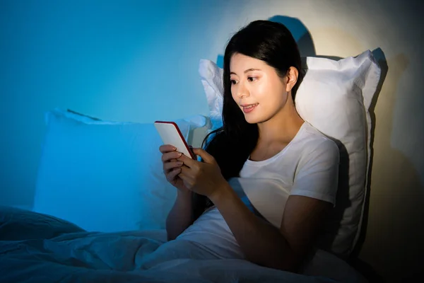 Las mujeres asiáticas están utilizando el teléfono inteligente en la cama — Foto de Stock