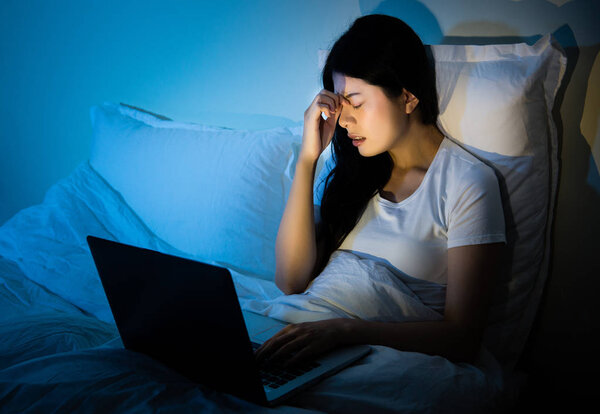 Unhappy woman with computer in the bed