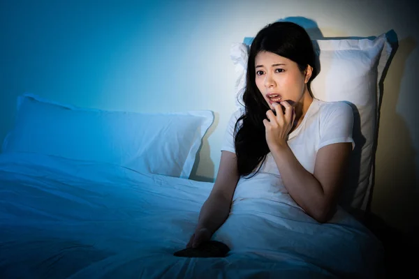 Chica sentada en la cama viendo la televisión una película de miedo — Foto de Stock