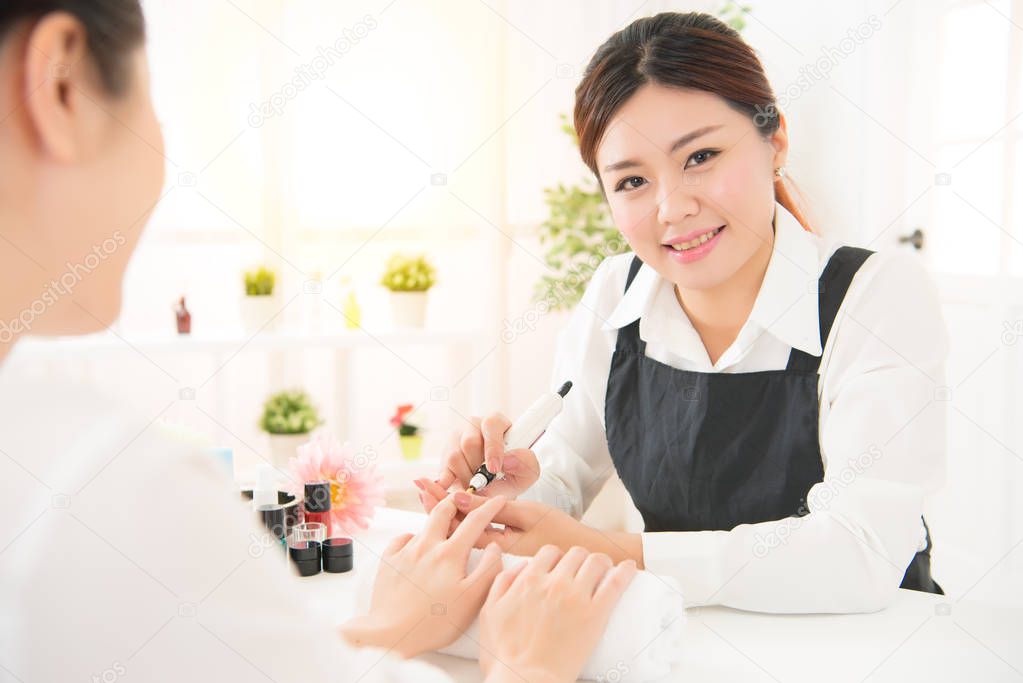 Manicurist is applying electric nail file drill