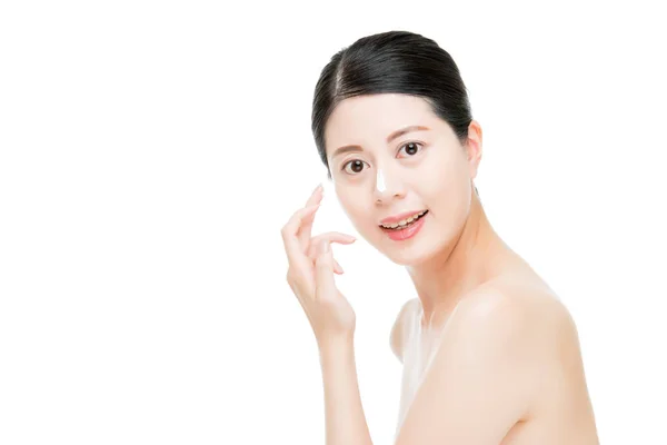 Aasialainen tyttö laittaa kermaa hänen palanut nenä . — kuvapankkivalokuva