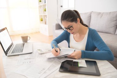 faturaları hesaplamak için laptop ve yastık kullanan kadın