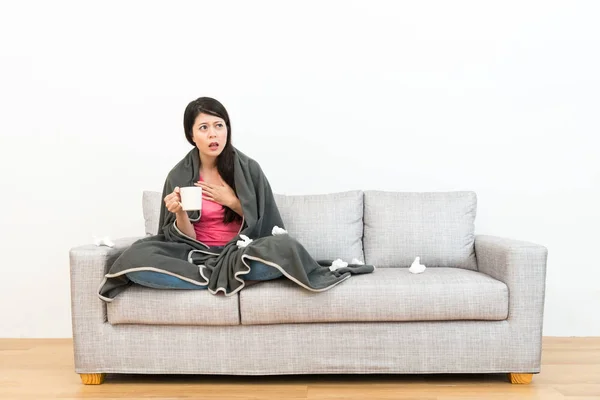 Студентка сидит на диване с горячей чашкой — стоковое фото