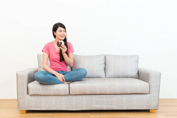 Femme assise sur le canapé regardant le fond blanc — Photo