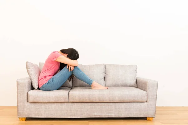 Wanita cantik muda sedih duduk di sofa — Stok Foto