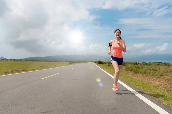 Prachtige vrouwelijke atleet lopen op asfaltweg — Stockfoto