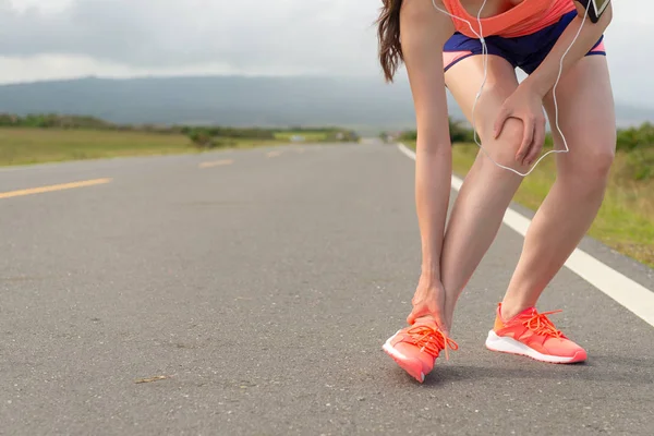 Female athlete ankle injury when running on road — Stock Photo, Image