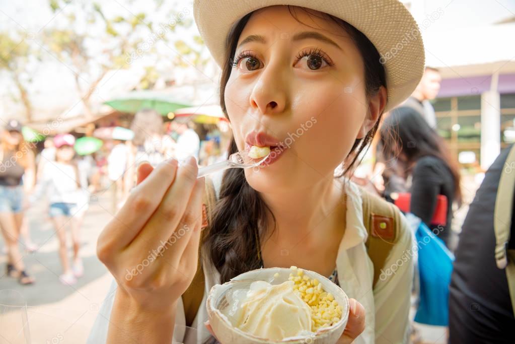 closeup of female traveler eating coconut ice cream