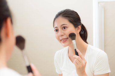 kozmetik kullanarak makyaj fırça tutan şirin kadın