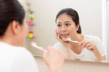 gülümseyen holding diş fırçası ve eli çeneme koymak