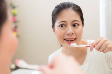 gülümseyen güzel kadın modeli diş fırçası tutan