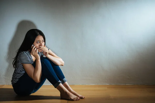 Jonge slachtoffer meisje zittend op houten vloer — Stockfoto