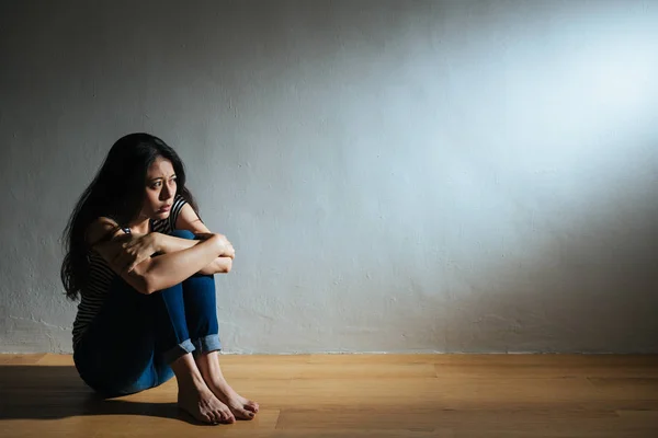 Tristeza jovem mulher sentada no chão de madeira — Fotografia de Stock