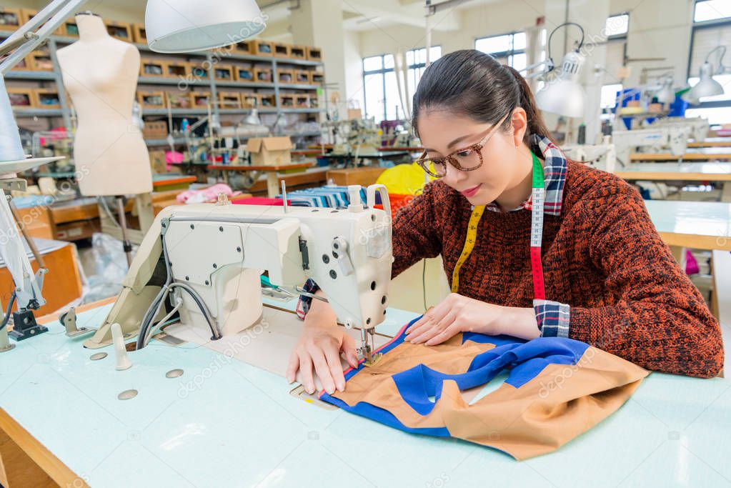 pretty female sewing worker using tailor machine