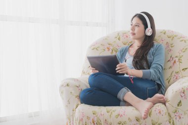 Dış manzaraya bakarak kanepede oturan kadın