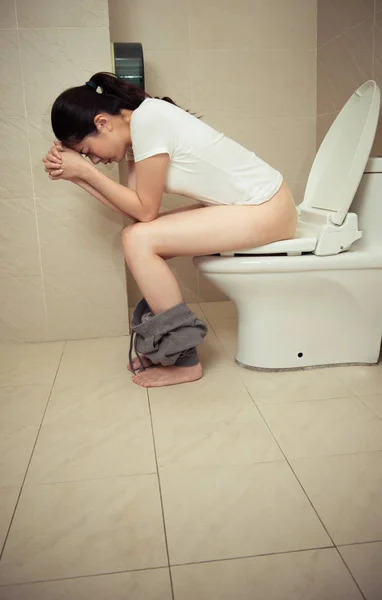 Attractive pretty woman sitting on bathroom toilet — Stock Photo, Image