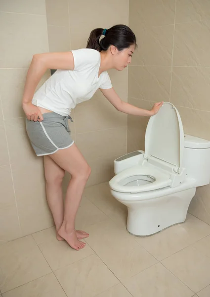 Linda mulher abrindo tampa do banheiro e segurando calça — Fotografia de Stock