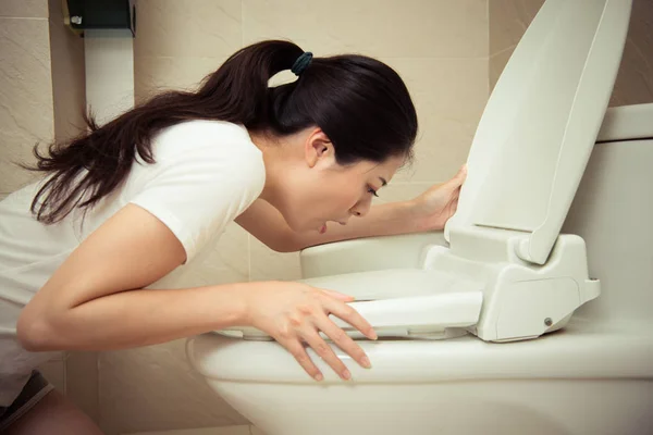 Nahaufnahme einer jungen hübschen Frau, die sich in Toilette erbricht — Stockfoto