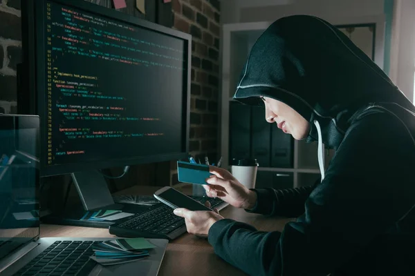 Hacker mit Kreditkarte und Handy — Stockfoto