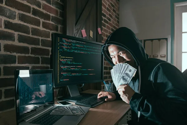 Злобный хакер, держащий наличные банкноты — стоковое фото
