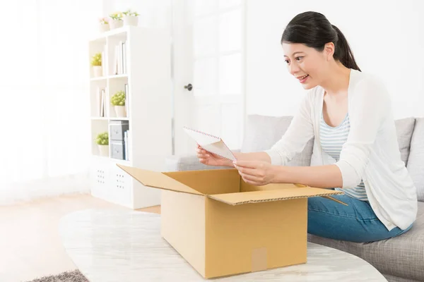 Mooi meisje zittend op de bank holding envelop — Stockfoto