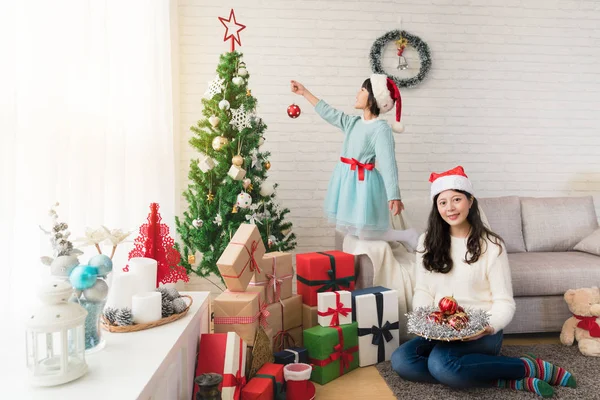 Mamman och flickan dekorera julgran — Stockfoto