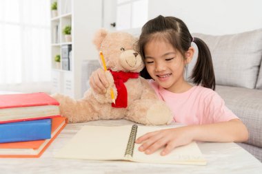 küçük kız onu teddy ile ödev gülümseyen