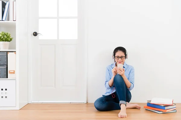 Joven dama con auriculares sentado en el suelo de madera — Foto de Stock