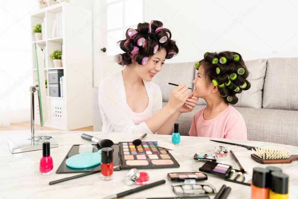 smiling beautiful woman helping little girl makeup