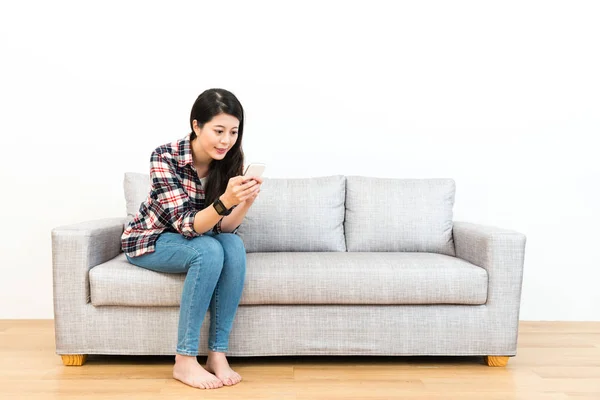 Lächelnde junge Frau auf Holzboden-Sofa — Stockfoto