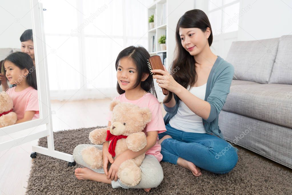 mom using brush to help daughter combing hair