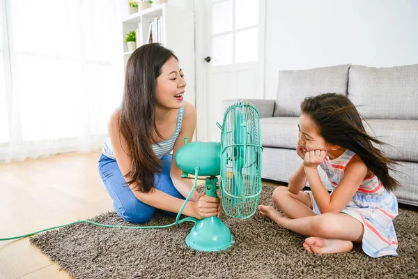Mother using fan helping daughter refreshing — Stock Photo, Image