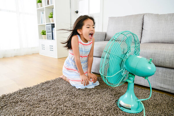 happy little girl playing electric fan at home