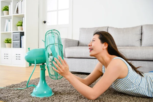 Lady lying down on floor and using electric fan — Stock Photo, Image