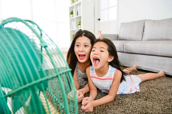 Маленькая девочка с матерью играет электрический вентилятор — стоковое фото