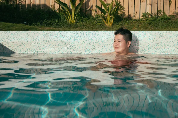 Улыбающийся молодой человек сидит в бассейне — стоковое фото