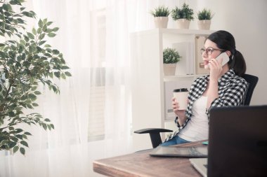 Mobil cep telefonu kullanarak genç kadın ofis çalışanı