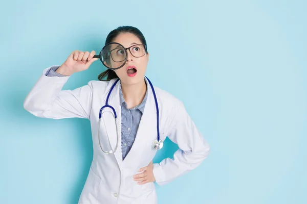 Jonge vrouwelijke arts permanent op blauwe achtergrond — Stockfoto