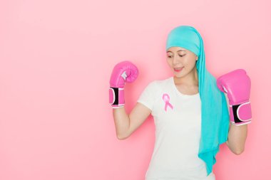 happy beauty girl having cancer problem and wearing boxing gloves decided courage to fight illness isolated on pink background. clipart