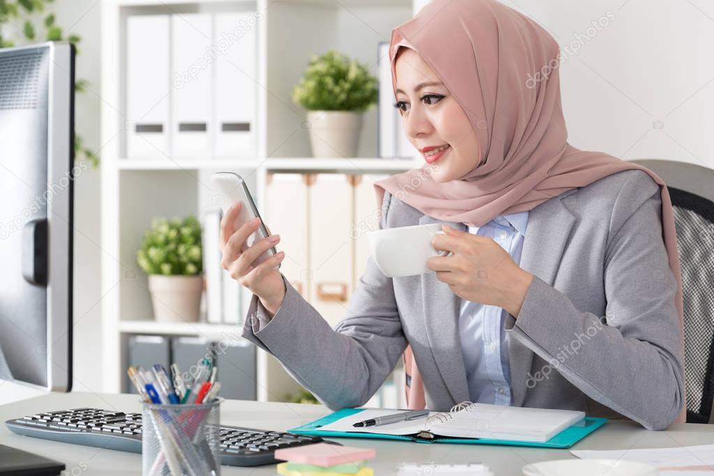 happy muslim female worker holding hot coffee mug