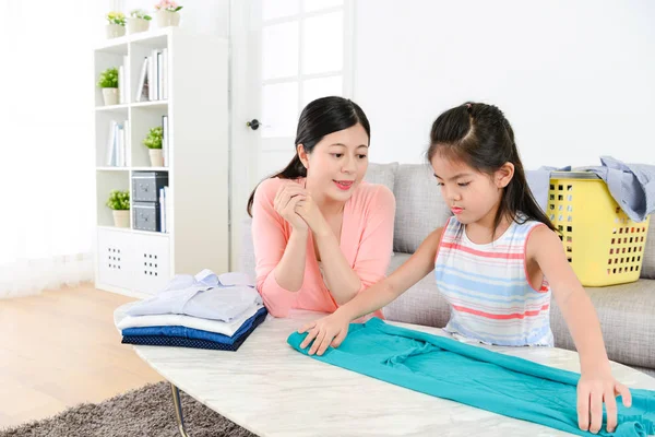 Atractiva niña aprendiendo ropa plegable — Foto de Stock