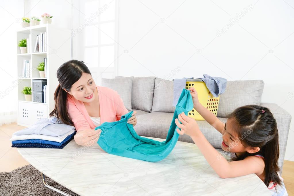 attractive little daughter folding family clothing