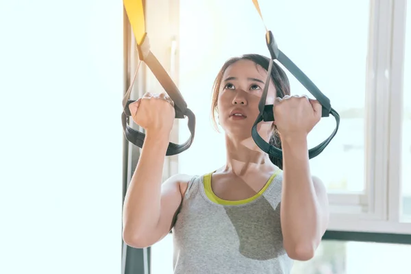 Charming Asian girl pulls up hard with TRX — Stock Photo, Image