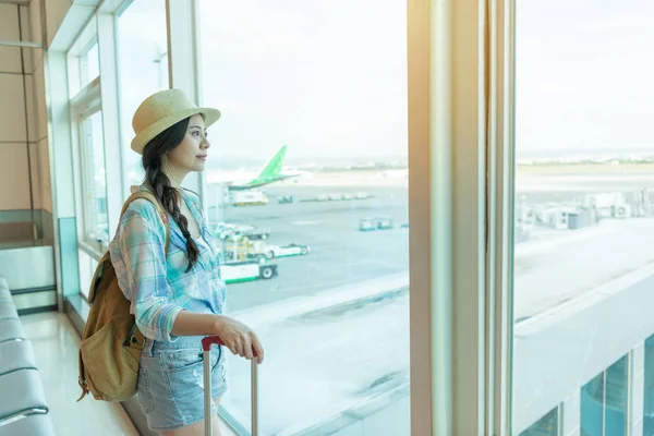 Путешественница смотрит в окно в аэропорту — стоковое фото