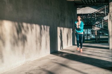 Boyunca bir kentsel gri duvar binalar çalışan kadın.